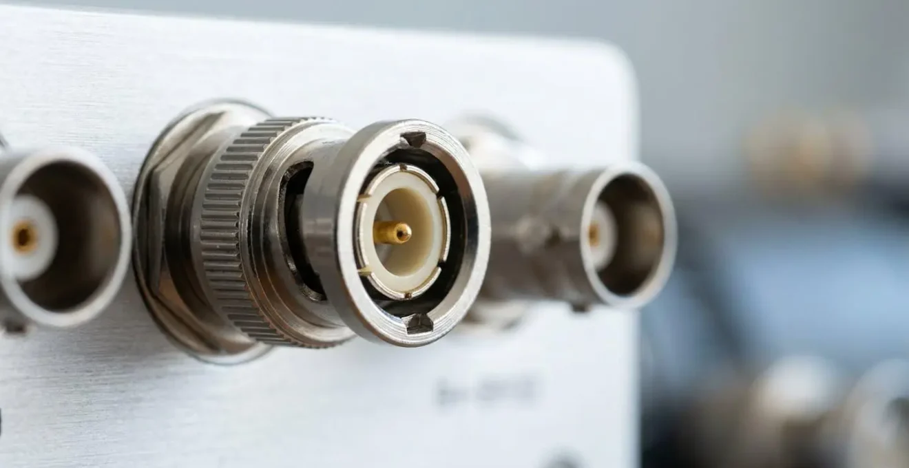 Gros plan macro sur des connecteurs professionnels broadcast 12G-SDI et câbles sur une surface propre, avec bokeh en arrière-plan